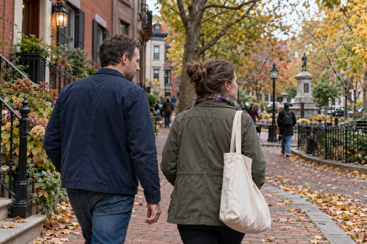Two adults walking side by side along a Philadelphia-style neighborhood street in autumn